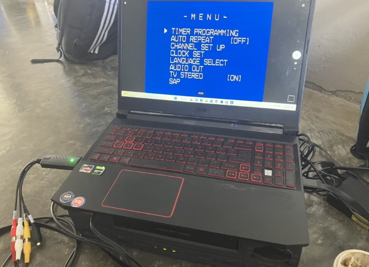 A computer on top of a vcr displaying the video on the vcr.